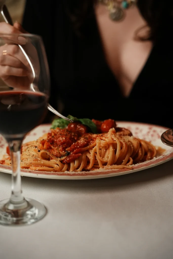 Assiette de pâtes à la tomate, verre de vin et convive, La Maison d’Anna