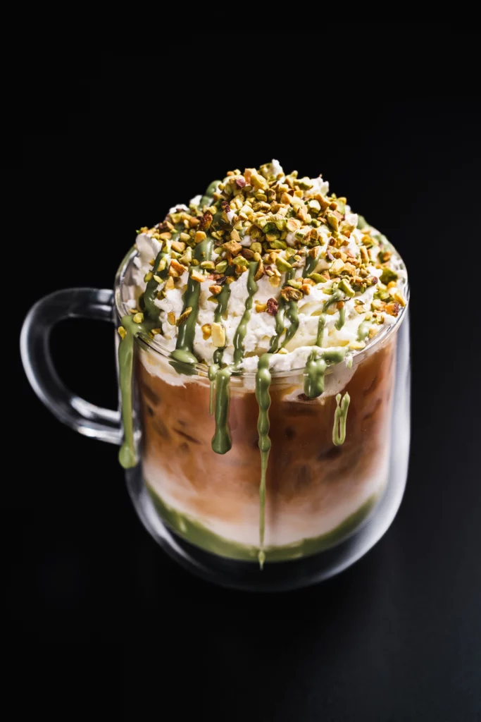 Création barista Bibal dans une tasse en verre, crème et éclats de pistache