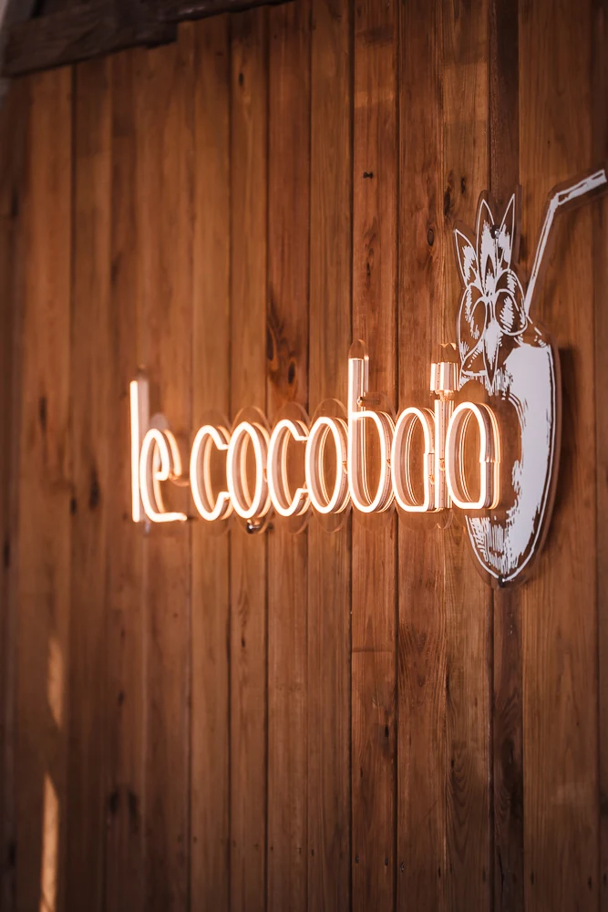 R&oacute;tulo luminoso Le Cocoba&iuml;a en la pared de madera