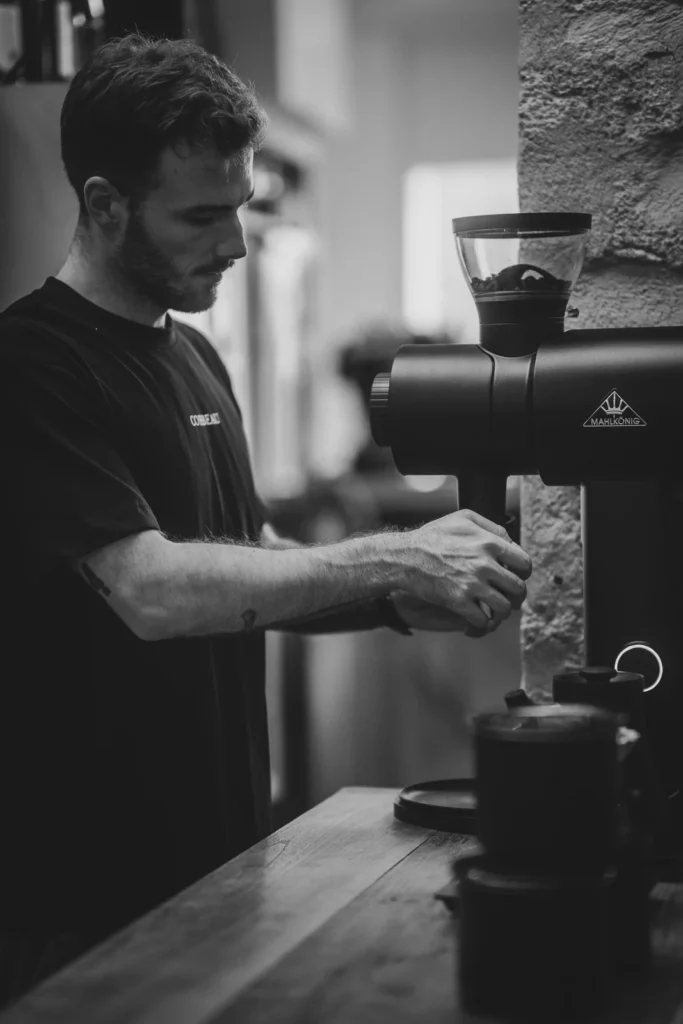 Le barista au moulin à café chez Corbeau, en noir et blanc
